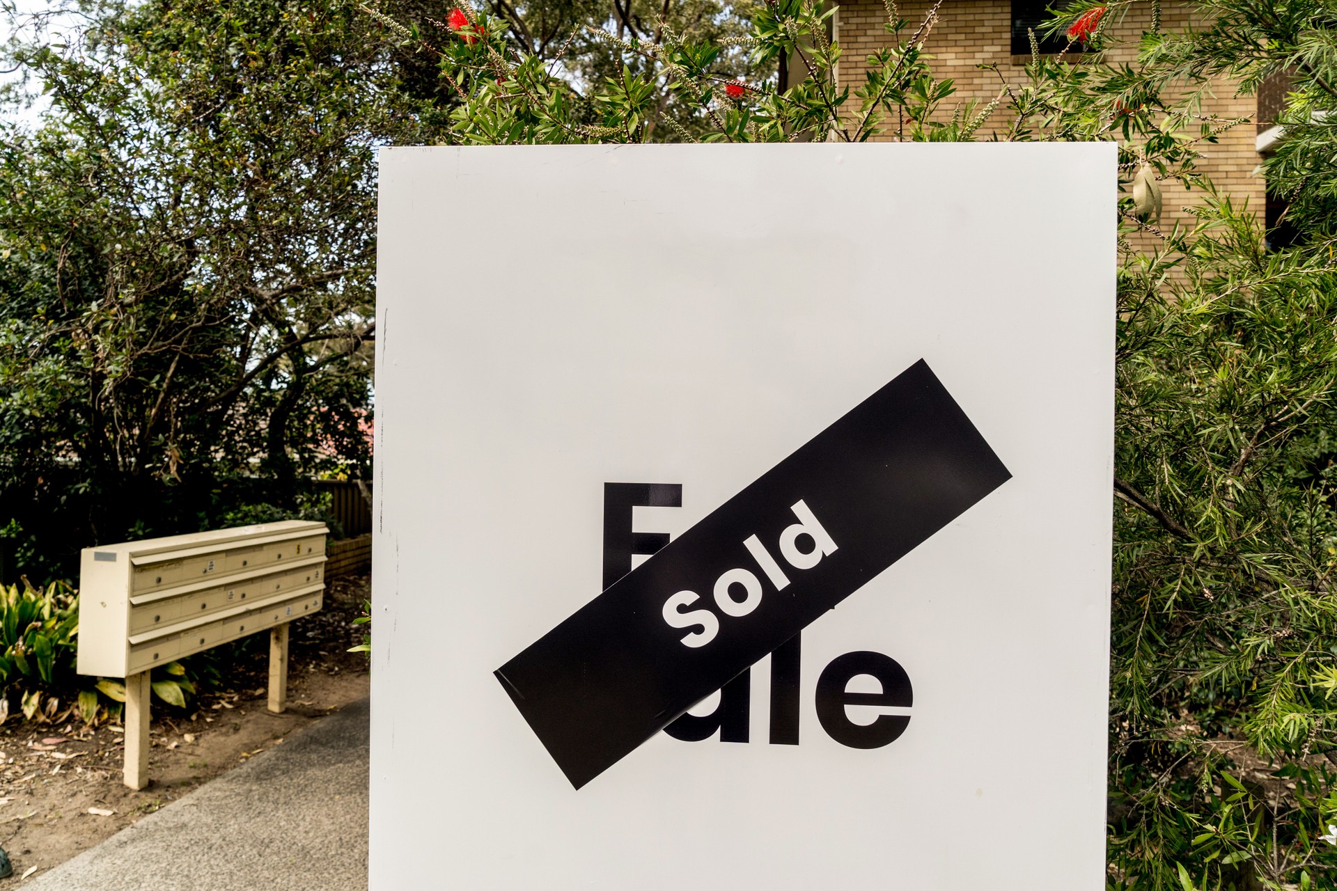 White for sale sign near the resedential appartment building with sold sticker on it. Real estate property investment boom concept